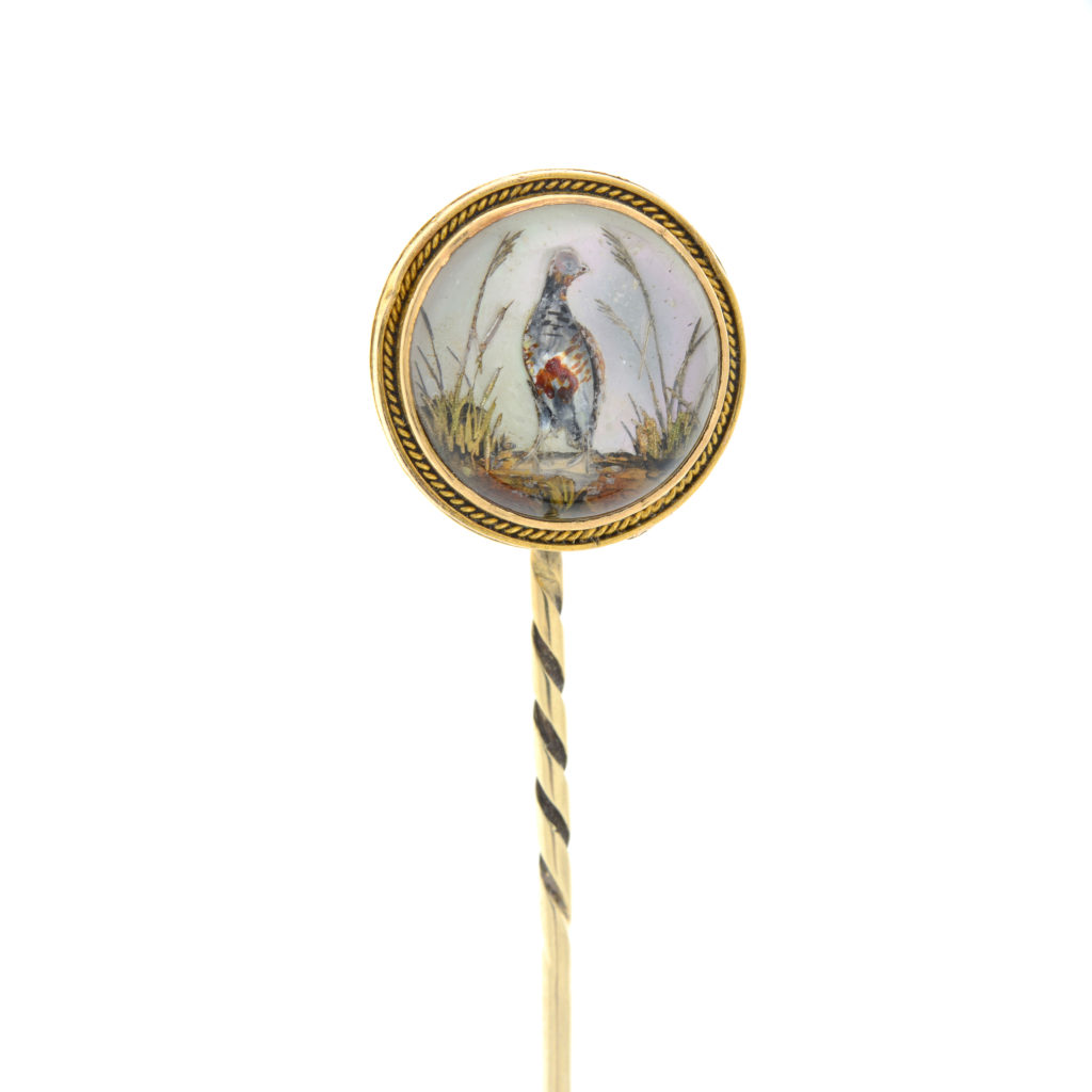 An early 20th century gold Essex rock crystal stick pin, depicting a game bird.