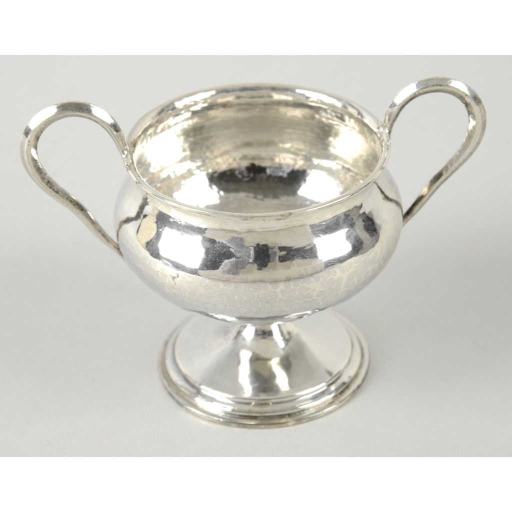 An Arts & Crafts style hammered silver twin-handled cup by Omar Ramsden.